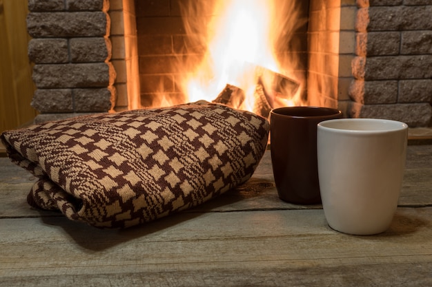 Scène confortable près de la cheminée avec des tasses de thé chaud et un foulard chaud.