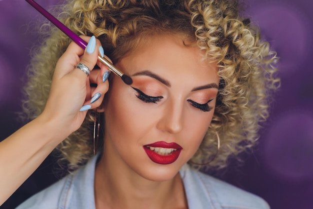 Scène dans les coulisses Maquilleur professionnel faisant du maquillage de modèle glamour au travail