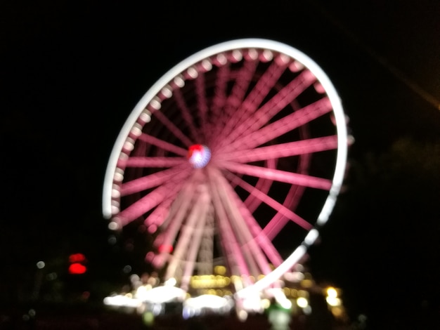 Scène défocalisé de grande roue de flyer rose géant dans la nuit