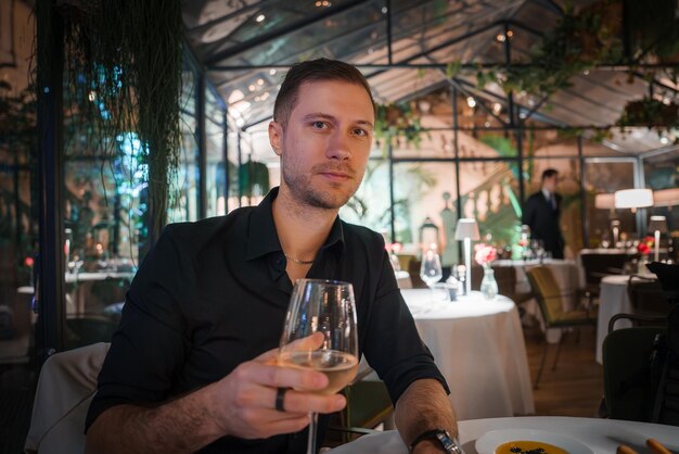 Scène de dîner luxueuse avec un homme dégustant du vin blanc dans un restaurant élégant