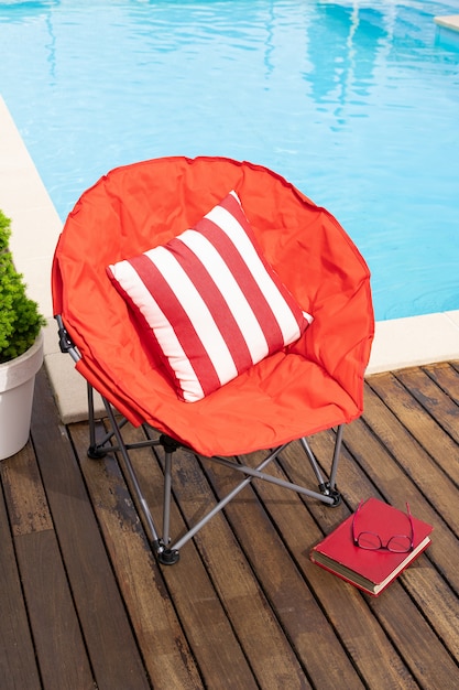 Scène d'été avec piscine, chaise, boisson et livre. Concept de vacances ou de loisirs en été.