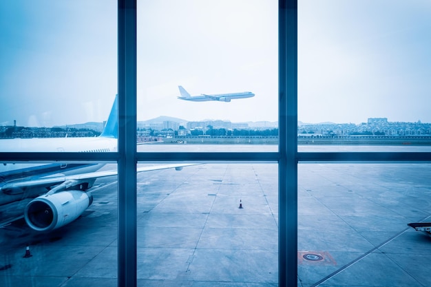 Scène de fenêtre d'aéroport un ton bleu de vol au départ