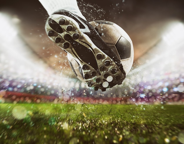 Photo scène de football au match de nuit avec gros plan d'une chaussure de football frappant la balle avec puissance