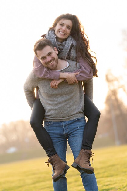 Scène heureuse et romantique avec un jeune couple hétérosexuel marchant et jouant dans un parc le jour de la saint-valentin