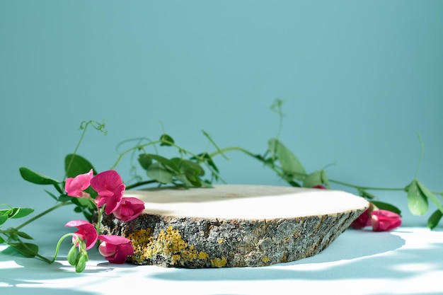 Scène minimaliste d'un podium en bois sur fond bleu clair avec des fleurs