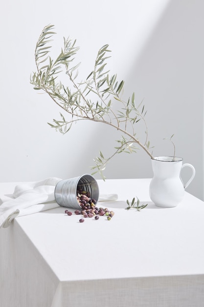 Scène minimaliste avec table blanche et seau à olives