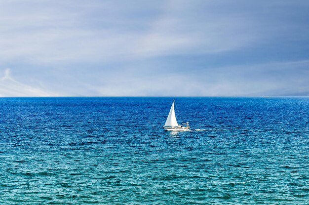 Scène d'un petit bateau à voile au milieu de l'océan bleu