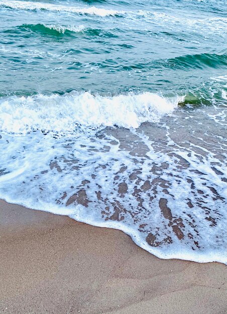 Une scène de plage avec une eau bleue et des vagues blanches