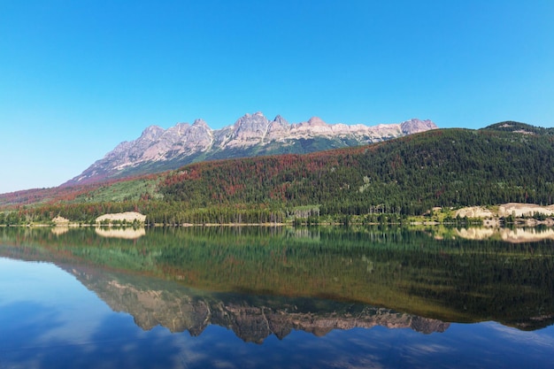 Scène sereine au bord du lac de montagne au Canada avec reflet des rochers dans l'eau calme.