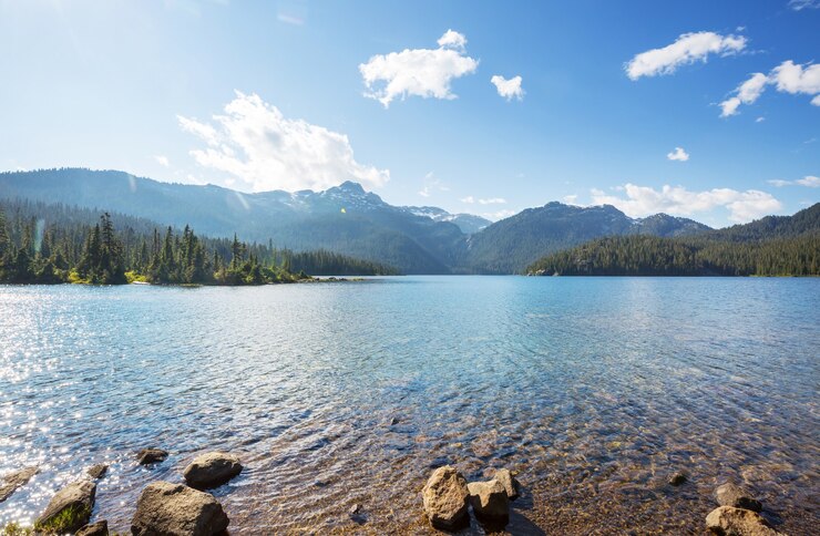Scène sereine au bord du lac de montagne au Canada avec reflet des rochers dans l'eau calme.