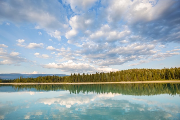 Scène sereine au bord du lac de montagne au Canada avec reflet des rochers dans l'eau calme.