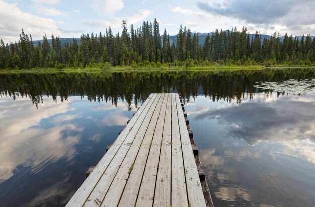 Scène sereine au bord du lac de montagne au Canada avec reflet des rochers dans l'eau calme.