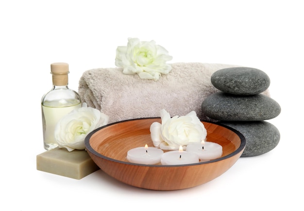 Scène de spa relaxante avec des bougies, des fleurs et des pierres sur une table en bois dans un centre de bien-être