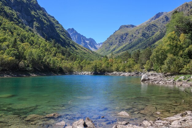 Scènes de lac dans les montagnes, parc national Dombai, Caucase, Russie, Europe. Temps ensoleillé, ciel bleu, arbres verts au loin. Jour d'été coloré, temps