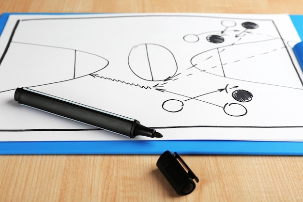 Photo schéma de jeu de basket-ball sur papier clipboard avec marqueur et fond de table en bois