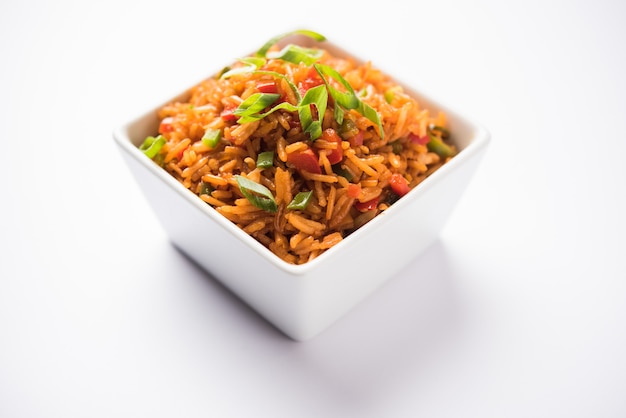 Schezwan Fried Rice Masala est un aliment indo-chinois populaire servi dans une assiette ou un bol avec des baguettes