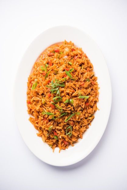 Schezwan Fried Rice Masala est un aliment indo-chinois populaire servi dans une assiette ou un bol avec des baguettes