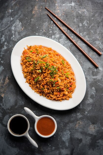 Schezwan Fried Rice Masala est un aliment indochinois populaire servi dans une assiette ou un bol avec des baguettes. mise au point sélective