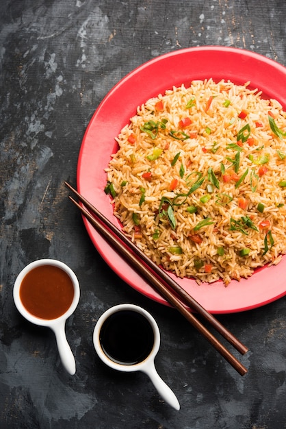 Photo schezwan fried rice masala est un aliment indochinois populaire servi dans une assiette ou un bol avec des baguettes. mise au point sélective