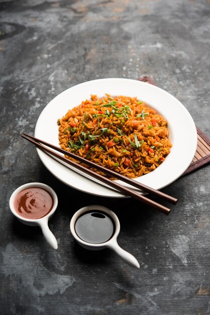 Schezwan Fried Rice Masala est un aliment indochinois populaire servi dans une assiette ou un bol avec des baguettes. mise au point sélective