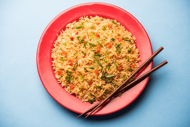 Schezwan Fried Rice Masala est un aliment indochinois populaire servi dans une assiette ou un bol avec des baguettes. mise au point sélective