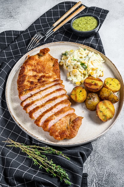 Schnitzel allemand weiner pané avec pommes de terre et salade. Fond gris. Vue de dessus