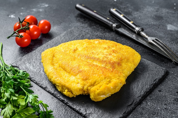 Schnitzel de poulet frit traditionnel. Fond noir. Vue de dessus.