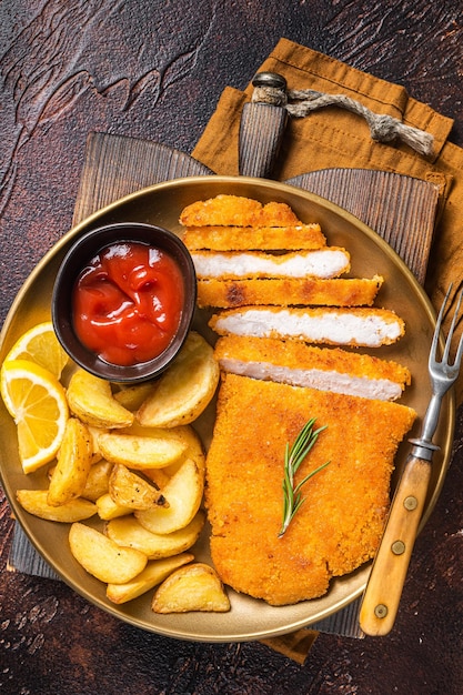 Schnitzel weiner allemand pané avec des quartiers de pommes de terre Fond sombre Vue de dessus