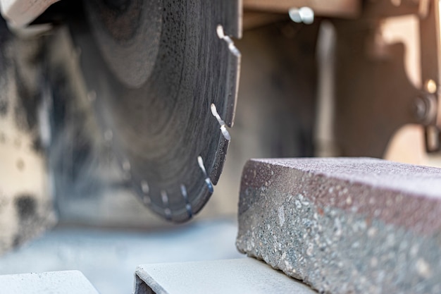 La scie circulaire diamantée coupe des dalles de pavage en béton. Gros plan de la machine de découpe de béton.