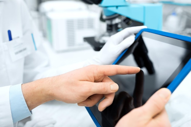 science, chimie, technologie, biologie et concept humain - gros plan des mains de scientifiques avec tablette pc en laboratoire