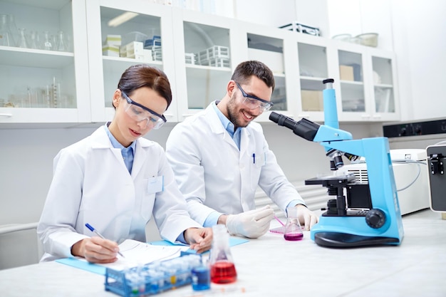 science, chimie, technologie, biologie et concept humain - jeunes scientifiques secouant le verre avec un réactif et effectuant des tests ou des recherches en laboratoire clinique