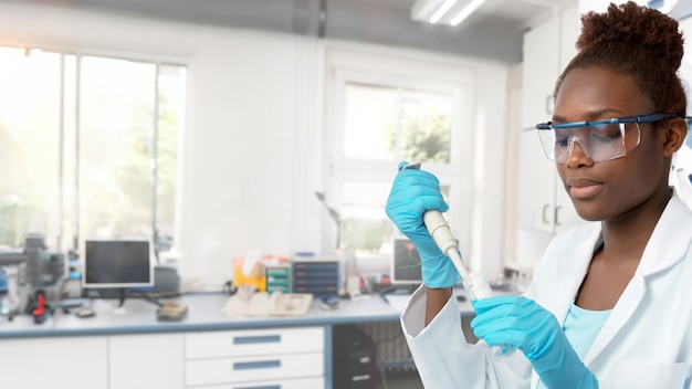 Photo une scientifique africaine ou une étudiante diplômée en blouse de laboratoire travaillant avec une pipette en laboratoire