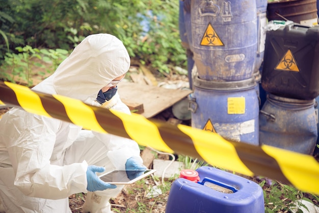 Un scientifique asiatique porte une combinaison de protection chimique, vérifie le danger chimique, travaille dans une zone dangereuse, authentifie les produits chimiques dangereux.