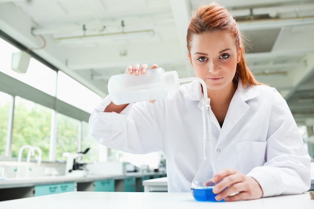 Photo scientifique aux cheveux roux, verser le liquide dans une fiole