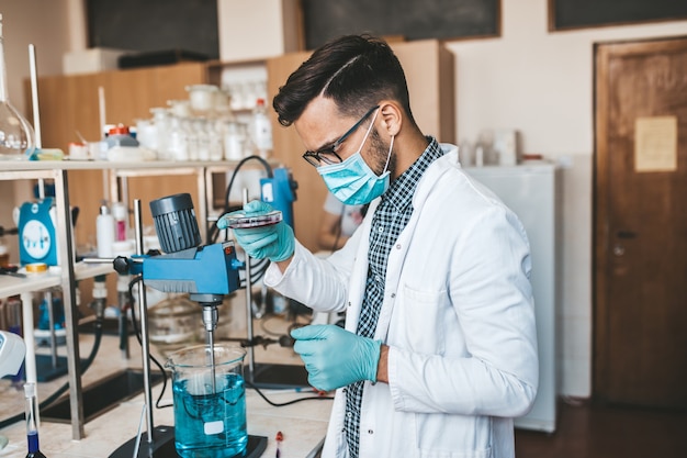 Un scientifique et chercheur d'âge moyen avec un masque de protection faciale travaille dans un laboratoire de chimie sur le vaccin contre le coronavirus.