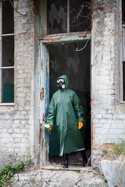 Un scientifique dosimétriste en vêtements de protection et un masque à gaz examine la zone de danger Gros plan fleur dans les mains