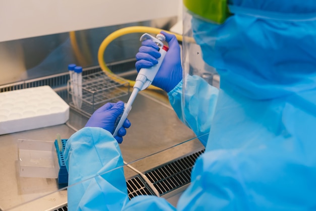 Photo un scientifique en epi safty expérience d'échantillon de pipetage uniforme dans une enceinte de sécurité biologique (bsc).