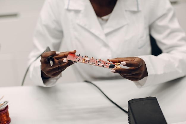 Scientifique femme afro-américaine travaillant en laboratoire avec fer à souder recherche et développement d'appareils électroniques par couleur femme noire