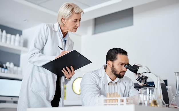 Scientifique homme femme et microscope avec liste de contrôle en laboratoire pour la recherche dans une société pharmaceutique Analyse de données de l'équipe scientifique et biotechnologie pour les objectifs vision et étude du virus avec travail d'équipe en laboratoire