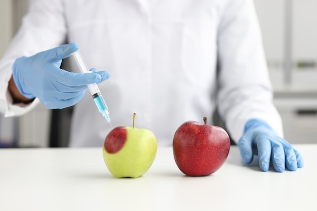 Un scientifique en laboratoire fait une injection dans une pomme. Concept d'hormone de maturation pour les légumes et les fruits