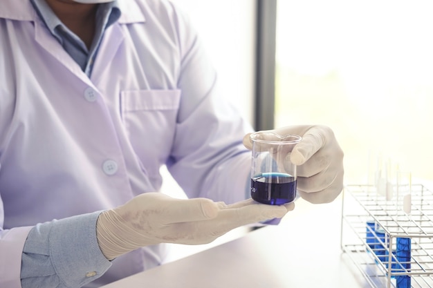 Scientifique ou médecin en blouse de laboratoire tenant un tube à essai avec réactif