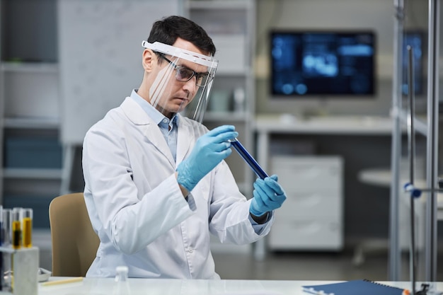 Scientifique portant un écran facial en laboratoire et tenant un tube à essai