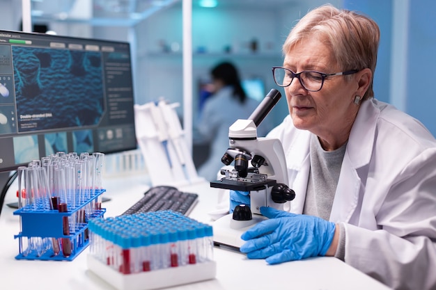 Scientifique principal en pharmacie travaillant avec un microscope professionnel dans la découverte de la clinique