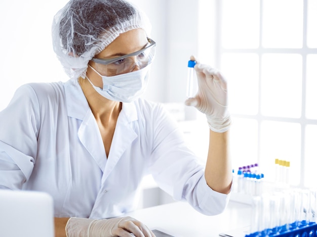 Photo scientifique professionnelle dans des lunettes de protection recherchant un tube avec des réactifs en laboratoire. concepts de la médecine et de la recherche scientifique.