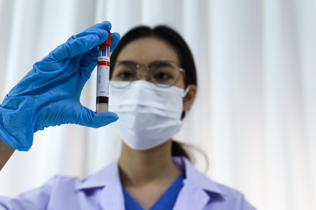 Photo scientifique tenant un tube d'échantillon de sang infecté par le coronavirus covid19 test adn du sang en laboratoire avec des tubes de prélèvement d'échantillons de sang et une seringue recherche sur le vaccin coronavirus covid19
