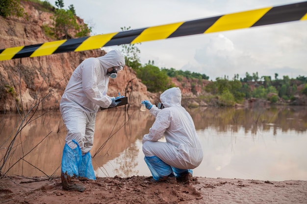 Des scientifiques ou des biologistes portant des uniformes de protection travaillant ensemble sur l'analyse de l'eau. Des ingénieurs environnementaux inspectent la qualité de l' eau dans une zone dangereuse.
