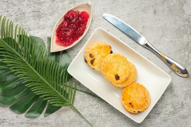 Scone en plaque blanche et confiture de fraises sur fond de ciment