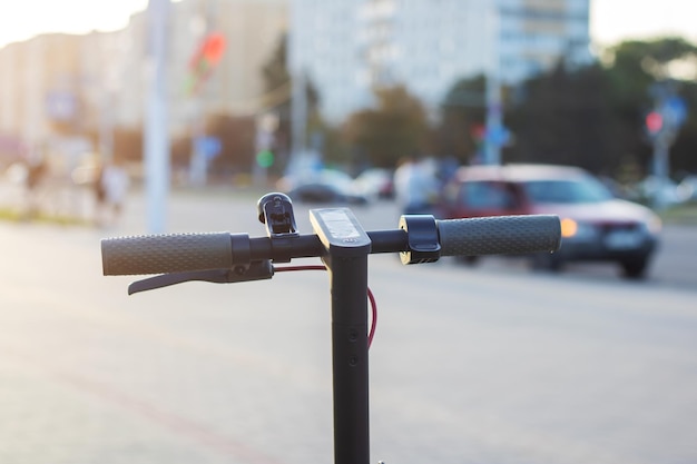 Scooter électrique sur fond de ville au coucher du soleil en gros plan