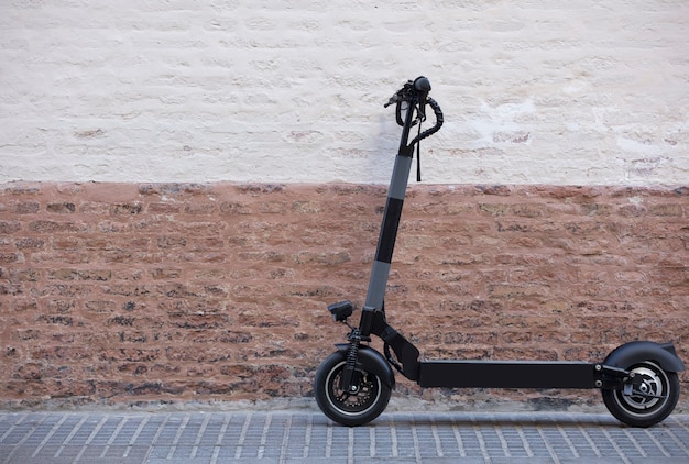 Scooter électrique de véhicule de mobilité personnelle garé dans la ville avec le mur de briques rustique b