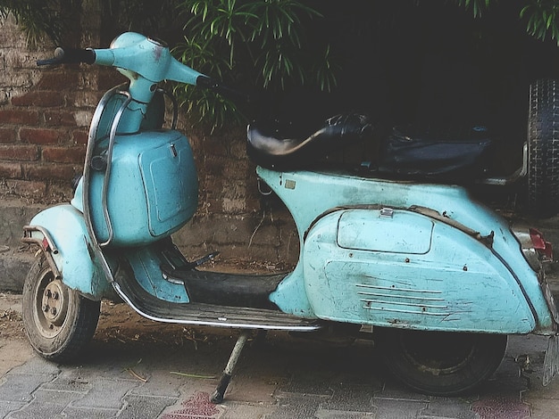 Un scooter à moteur turquoise garé près du mur.